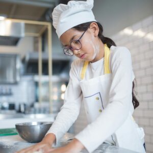 Child chef kneading dough in a contemporary kitchen, Portugal.